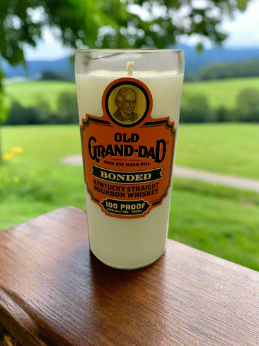 Old Grand-Dad bourbon candle on a wooden surface with a scenic background